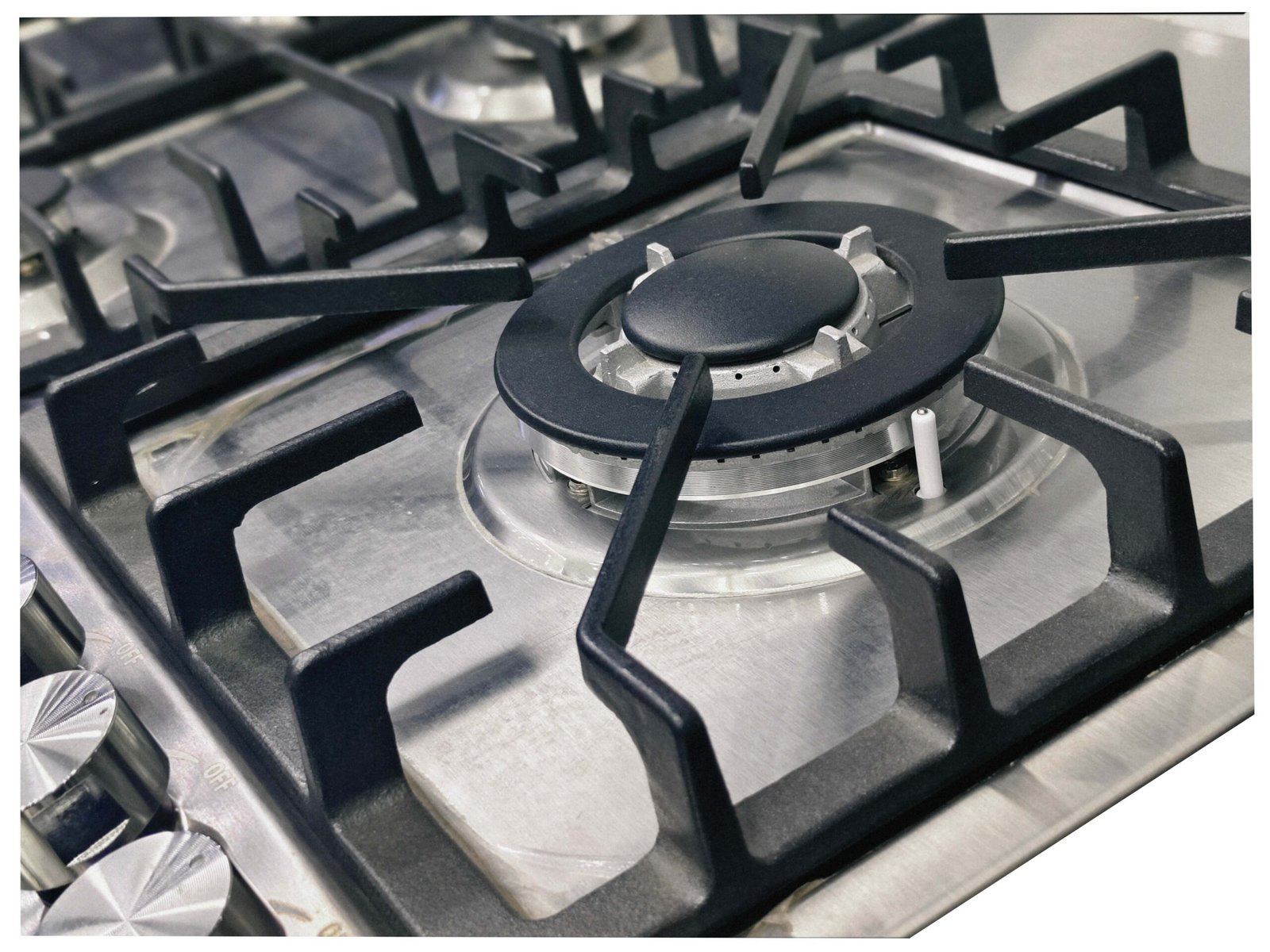 Close-up of a clean, unused stainless steel gas hob burner from image IMG_20240927_213033-scaled-1.jpg, featuring black pan supports and control knobs on the left side.