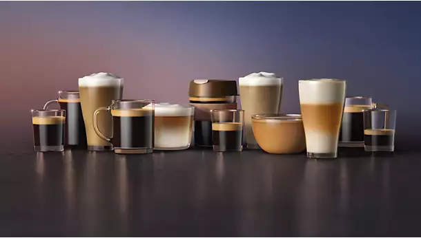 A selection of coffee drinks made with the vrs_5400-05-ac.webp coffee machine are displayed in assorted cups on a dark surface, each featuring different layers of milk, foam, and espresso, set before a blurred gradient backdrop.