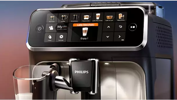 Close-up of a Philips vrs_5400-06-ac.webp fully automatic coffee machine with a digital touchscreen showing coffee options and a latte macchiato being selected; a glass under the spout is partially filled with milk.